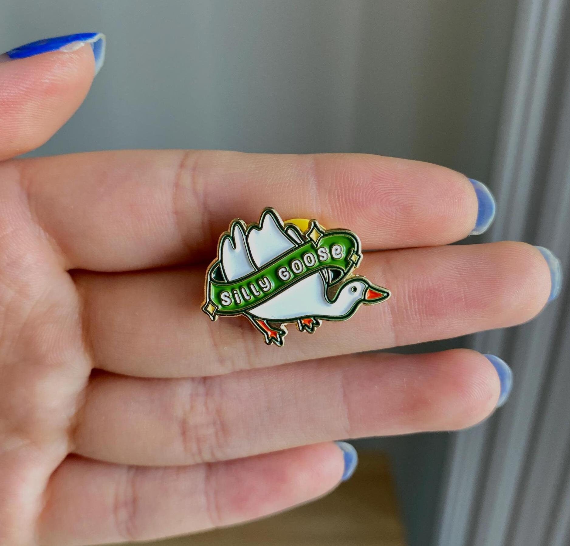 Goose enamel pin with a green banner that says &quot;silly goose&quot;