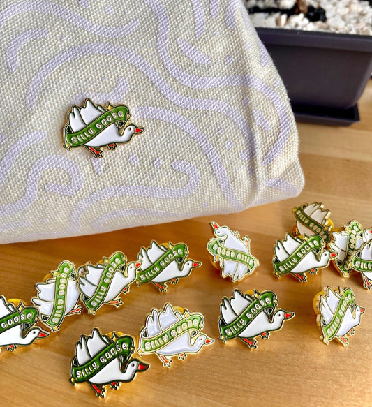 Enamel pin with a silly goose and green banner