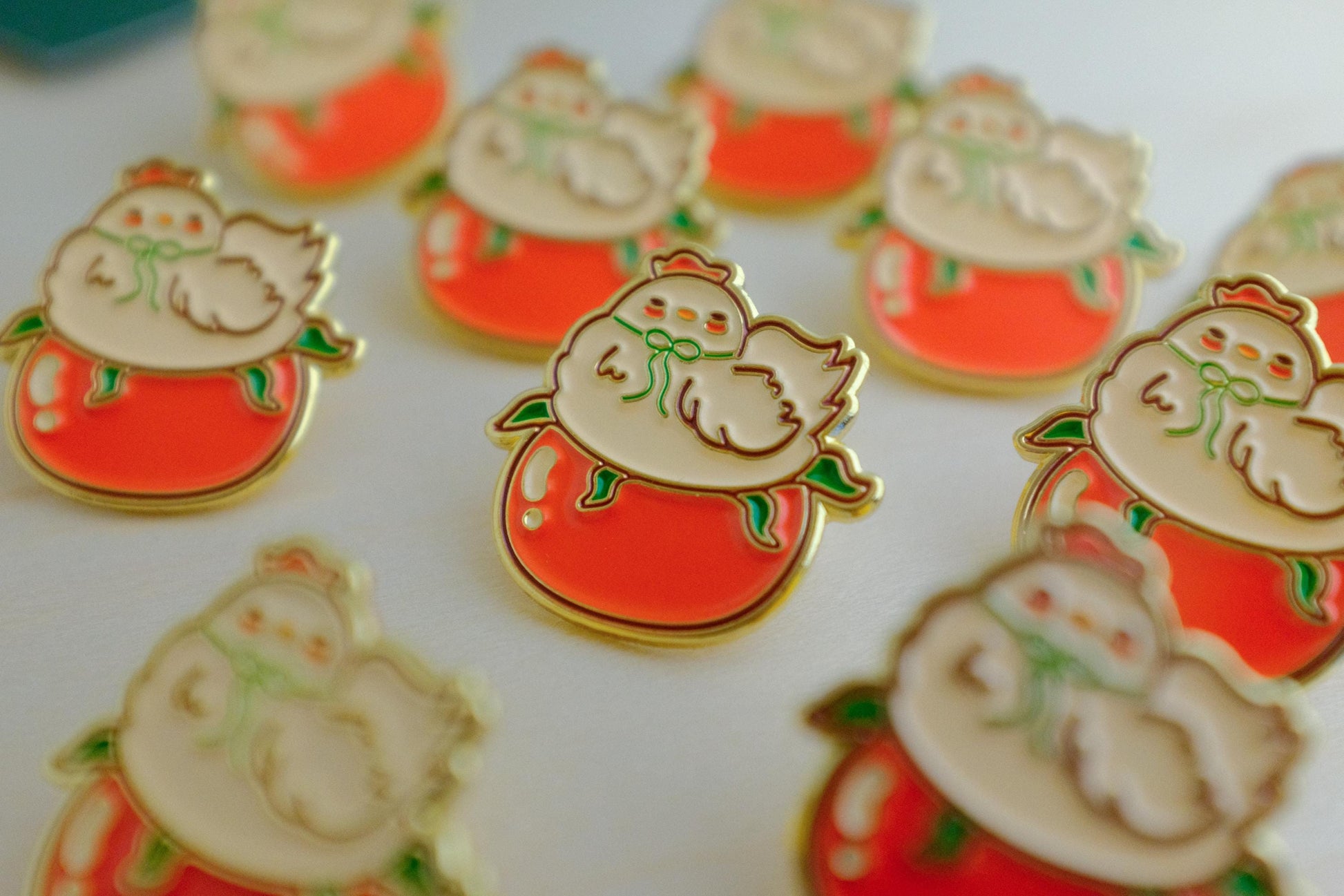 Cute chicken with green bow sitting on top of a red tomato enamel pin